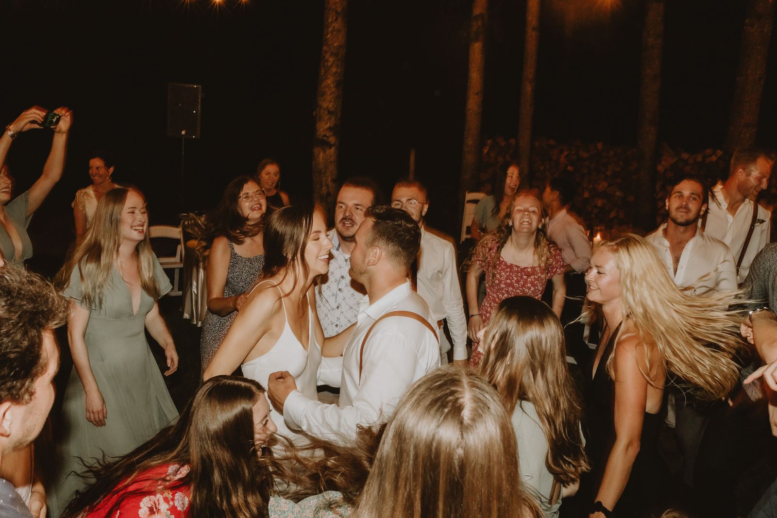 Guests dancing at an outdoor wedding reception under warm lights