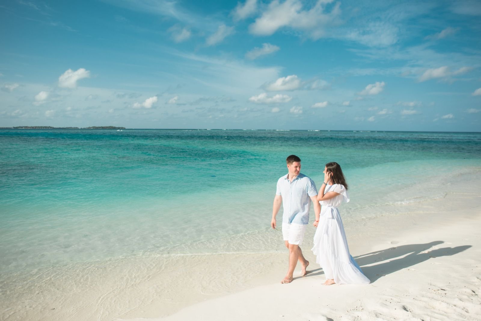 Newlyweds walking hand in hand along a tropical beach