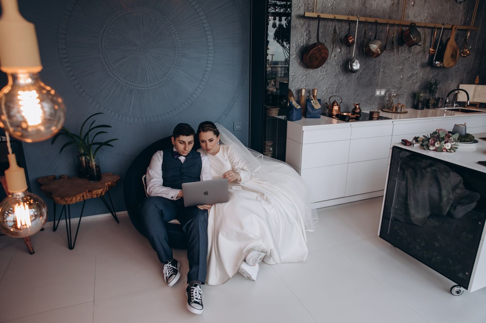 Bride and groom sitting together looking through their wedding photos on a laptop