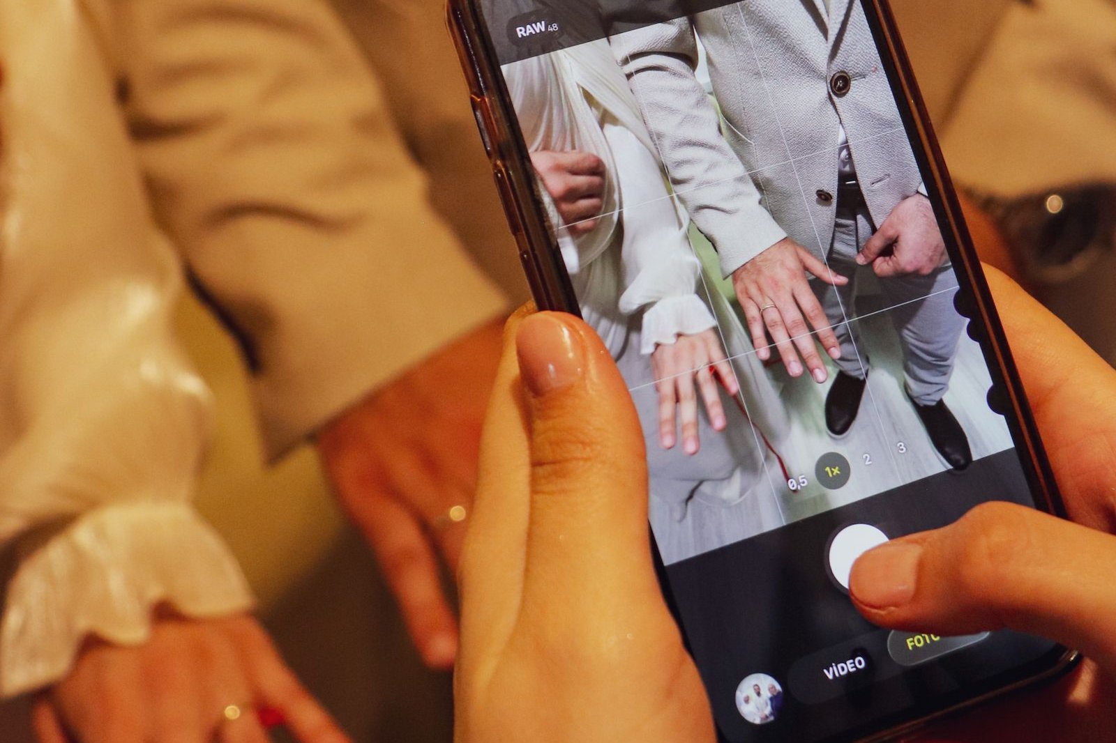 Close-up of a guest's hands photographing the bride and groom on a smartphone