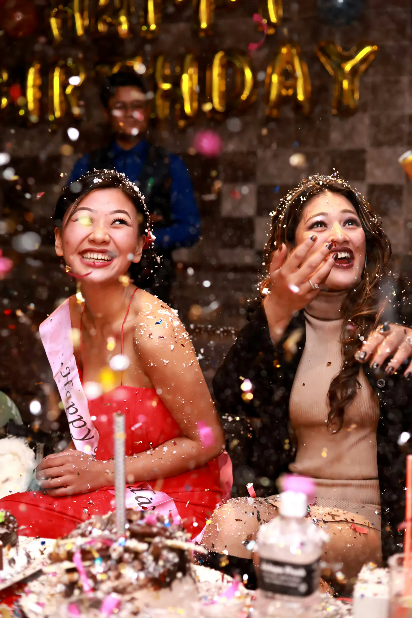 Friends laughing under confetti at a birthday party